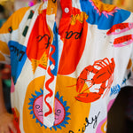 Close-up of the Sicily Calls Dress fabric showing the intricate summer print, partial button-down front, and ruched collar detail, made from breathable cotton with stretch.