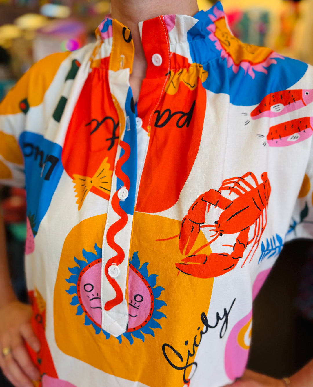 Close-up of the Sicily Calls Dress fabric showing the intricate summer print, partial button-down front, and ruched collar detail, made from breathable cotton with stretch.
