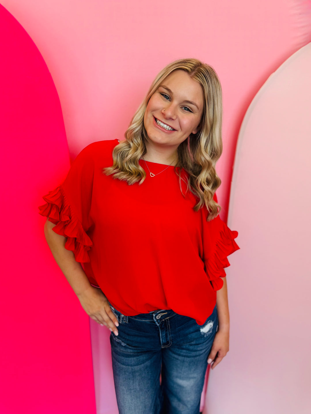 A vibrant red woven top featuring dramatic, multi-tiered pleated ruffle sleeves.