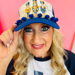 Nutcracker trucker hat with blue pom poms, snow patch accents, and three classic nutcracker characters.