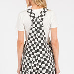 Black checkered knit romper overalls with cuffed shorts, chest and side pockets, and adjustable straps, laid flat to show texture and structure.