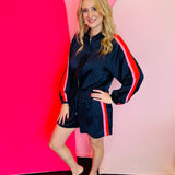 Navy track jacket with ruffle front, racing stripe sleeves, zip closure, and pockets.