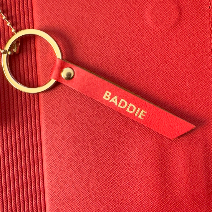 Red keychain with 'BADDIE' tag on a red background