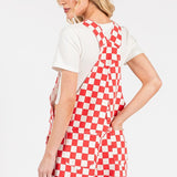 Red checkered knit romper overalls with adjustable straps, metal hardware, multiple pockets, and cuffed shorts, laid flat to highlight color and texture.