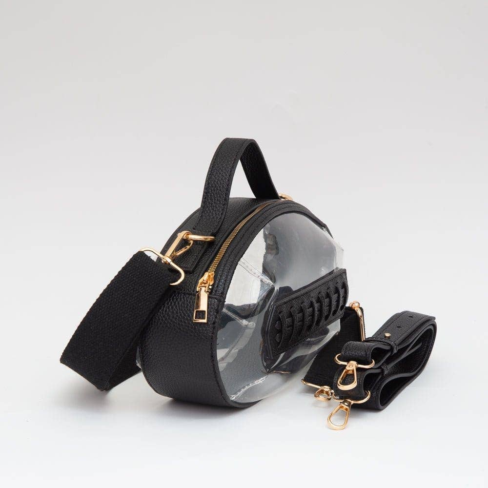 Clear football-shaped crossbody bag with black trim, gold hardware, top handle, and adjustable strap, laid flat to highlight shape and detailing.