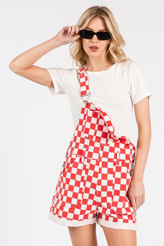 Red checkered knit romper overalls with adjustable straps, metal hardware, multiple pockets, and cuffed shorts, laid flat to highlight color and texture.