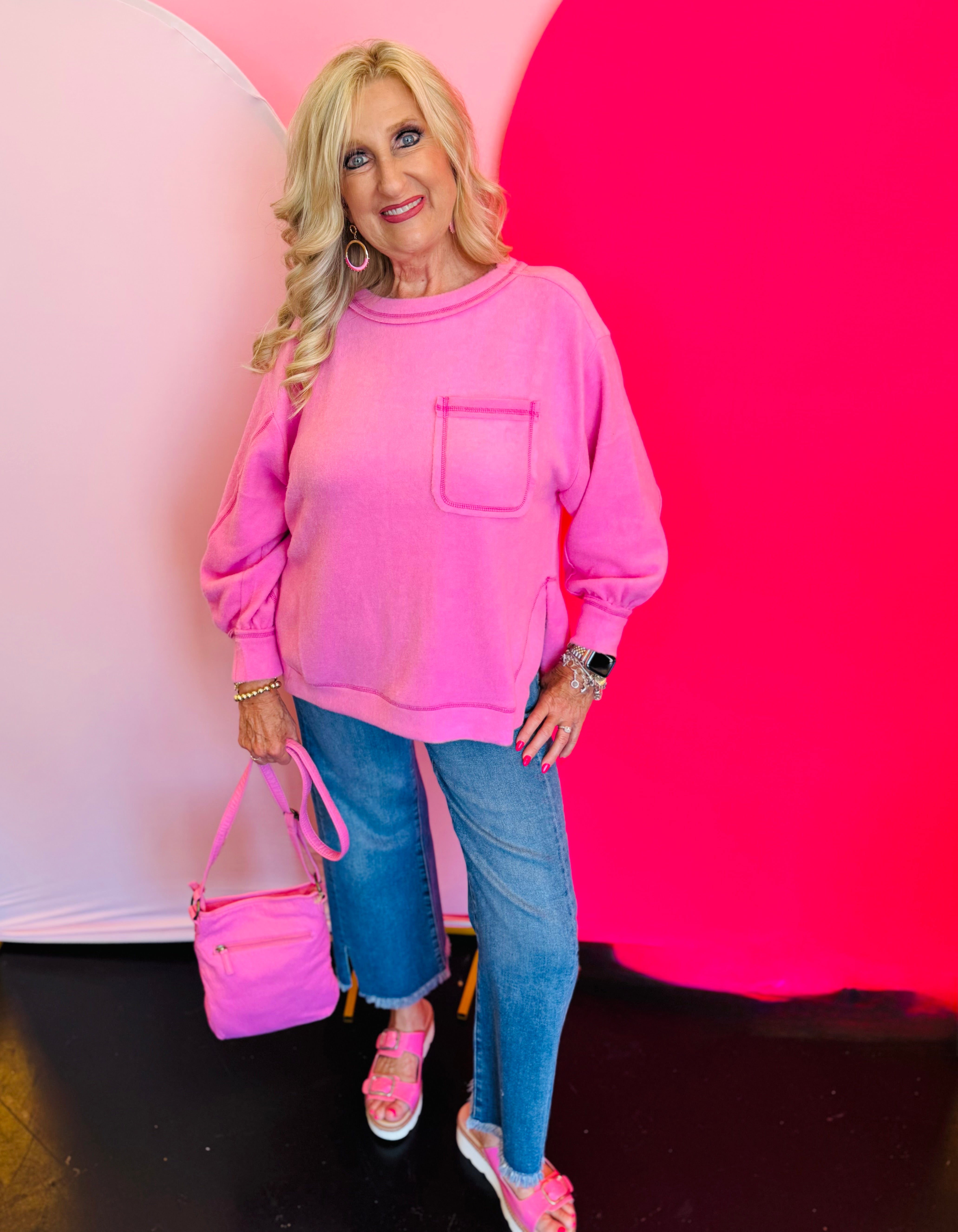 Full outfit shot featuring the Candy Pink Hi-Low Sweater paired with jeans and a coordinating pink purse for a cute and casual look.