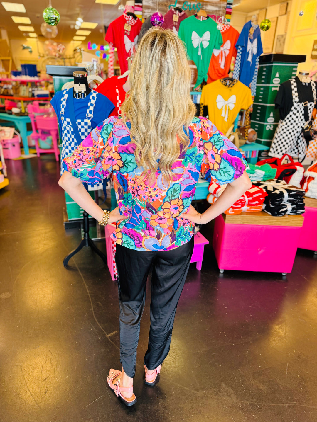 Vibrant floral print top in pink, orange, purple, and green with puff sleeves, round neckline, and contrast trim.