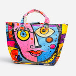 Glossy PVC tote bag with colorful pink, blue, yellow, orange, and purple abstract face design.