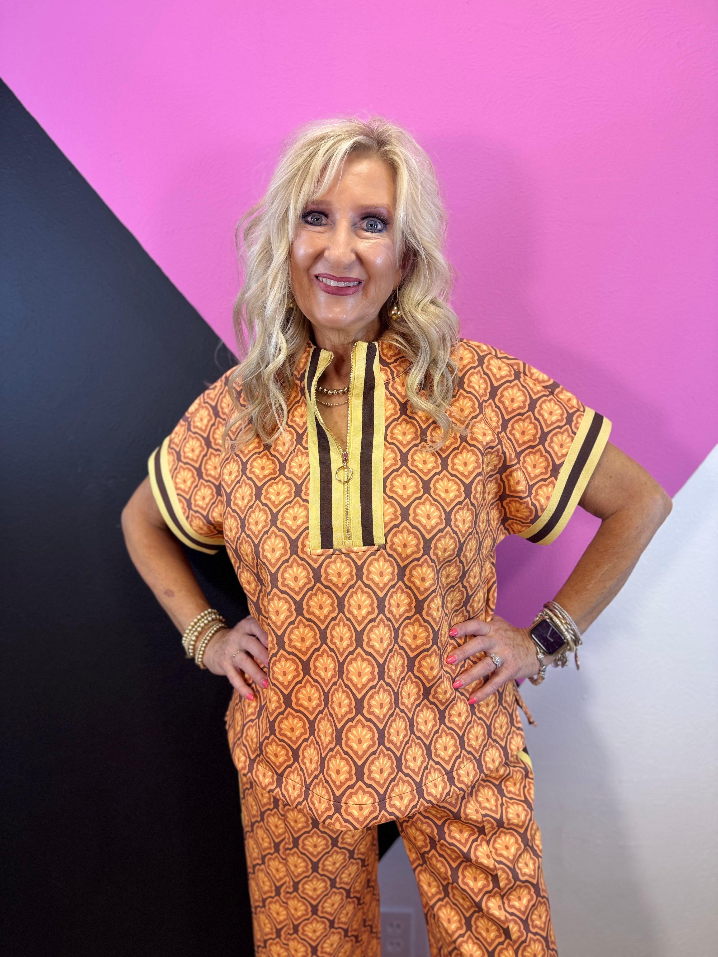 Brown rust and cream geometric quarter zip top with striped trim and side slits.