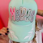 Mint trucker hat with colorful sequin “Merry” patch and white embroidered leaf accents on brim.