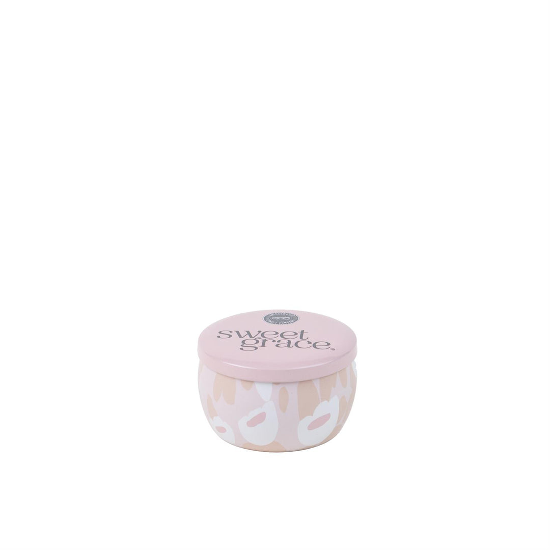 A small, round candle with a pink lid and white label featuring the fragrance name 'Sweet Grace'.