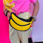 Yellow banana shaped crossbody bag with gold chain strap and zip closure.