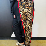 Black sweatpants with leopard side panels, red piping, elastic drawstring waist, and pockets.