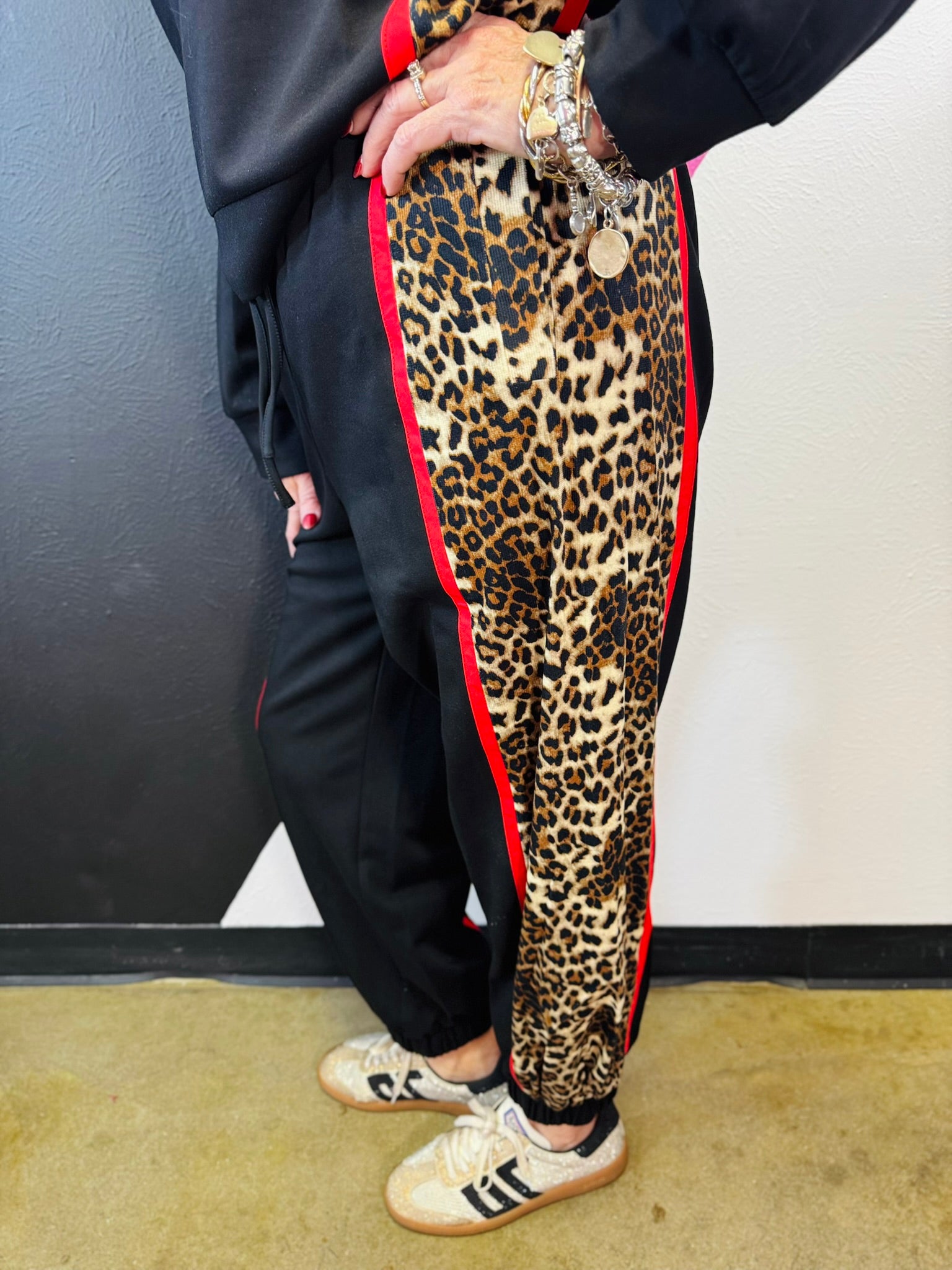 Black sweatpants with leopard side panels, red piping, elastic drawstring waist, and pockets.