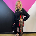Black long sleeve pullover with leopard side panels, red piping, and banded hem.