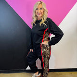 Black long sleeve pullover with leopard side panels, red piping, and banded hem.