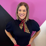 Black puff sleeve knit sweater with detachable leopard scarf neckline and bright red trim.