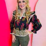 Black multi-print puff sleeve top with red and gold florals, ruffle shoulders.