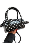 Black polka dot crossbody bag with top handles and adjustable strap.