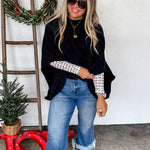 Black knit pullover poncho with relaxed fit, long arm openings, and cozy, flowy silhouette.