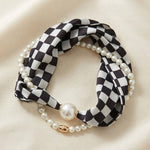 Black and white checkered scarf necklace with silky fabric and lustrous pearl accents.