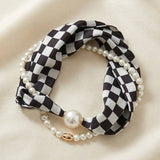 Black and white checkered scarf necklace with silky fabric and lustrous pearl accents.