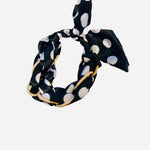Black polka dot knot bracelet with gold chain accents.