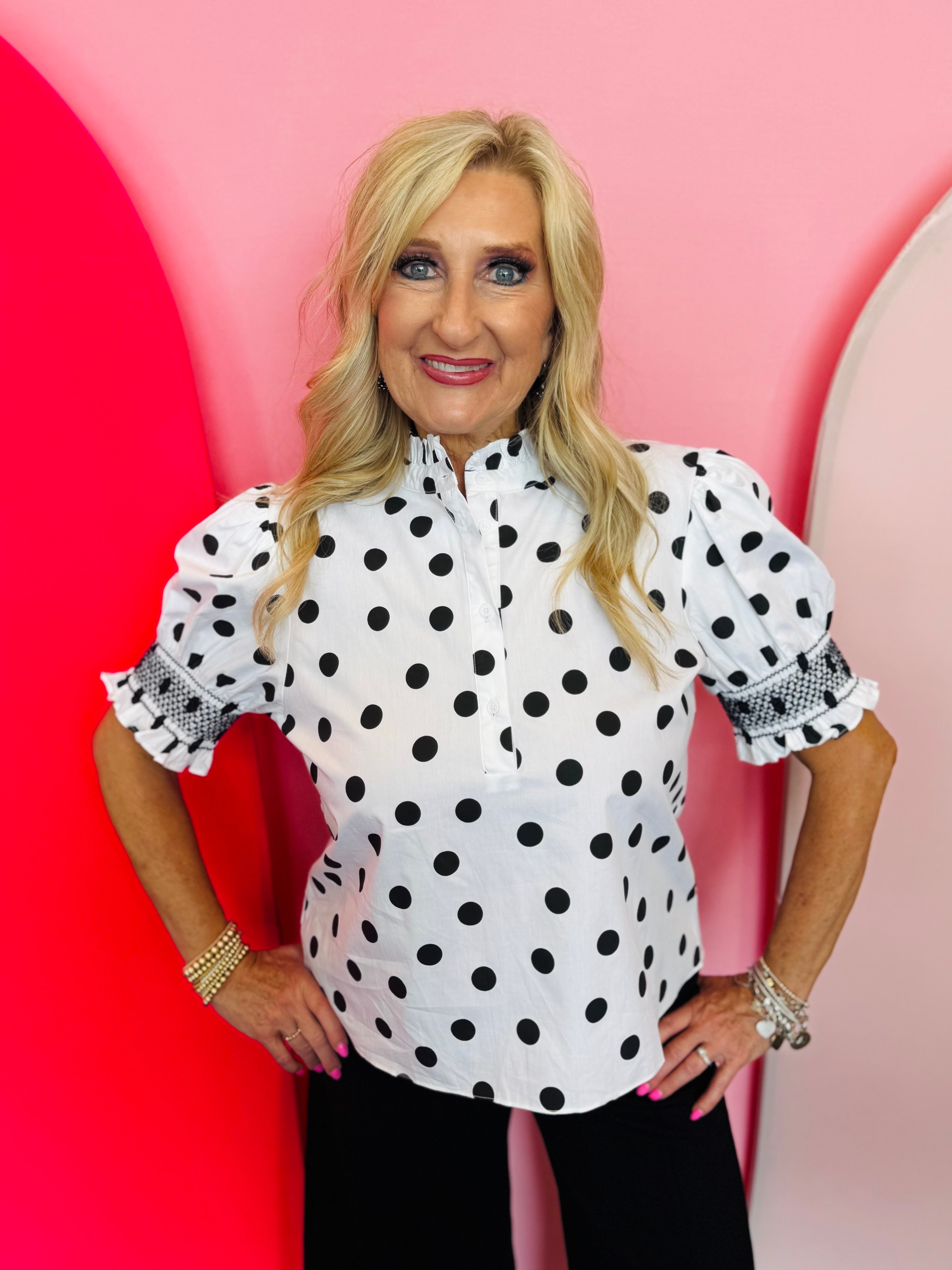 Black and white polka dot blouse with puff sleeves, ruffle neckline, and button-front detail.