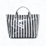Black and white striped glossy waterproof tote bag with pink interior and pockets.