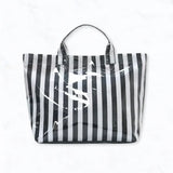 Black and white striped glossy waterproof tote bag with pink interior and pockets.