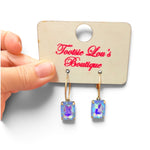 Gold-tone hoop earrings with faceted rectangular crystals reflecting iridescent blue tones.