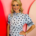 Blue polka dot blouse with puff sleeves, ruffle neckline, and button-front detail.