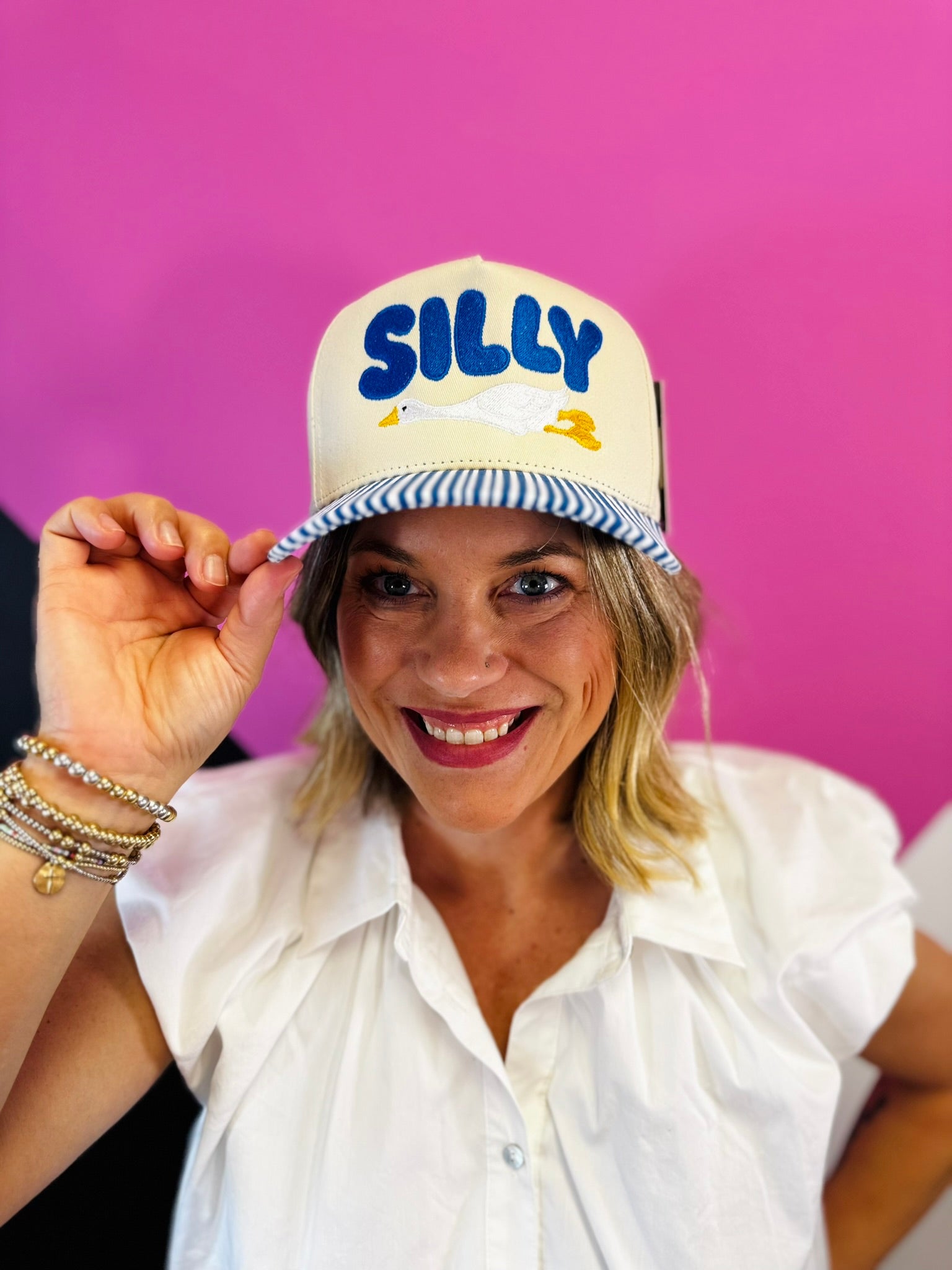 Cream Silly Goose hat with blue embroidery and striped bill.