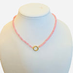 Blush Glow Necklace with faceted pink beads, gold central bead with charm clip, and magnetic clasp.