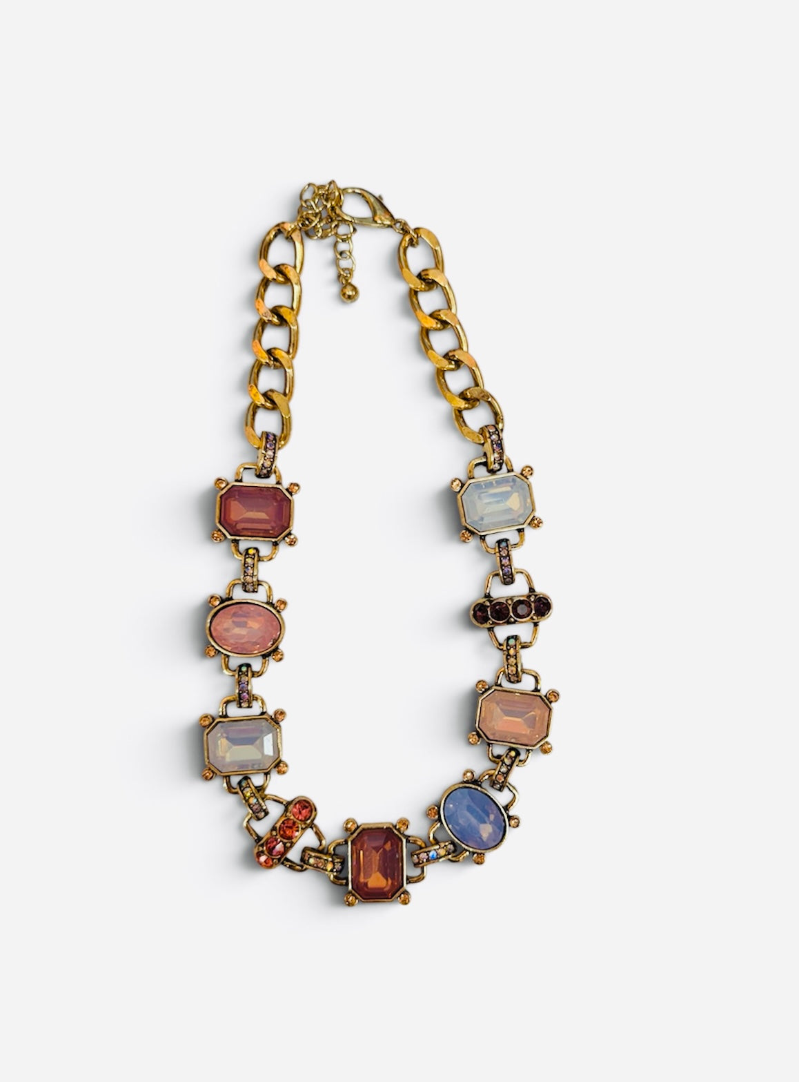 Chunky gold-tone link necklace with blush pink, amber, opalescent crystals, and rhinestone accents.