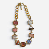 Chunky gold-tone link necklace with blush pink, amber, opalescent crystals, and rhinestone accents.