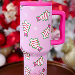 Pink Christmas tumbler with bow-topped holiday treats, hot pink handle, and reusable straw.