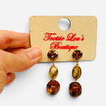 Brown and tan gemstone drop earrings with glossy beads and polished gold-tone settings.