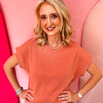 Burnt orange raised rib knit top with cap sleeves and boat neckline.