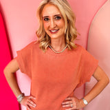 Burnt orange raised rib knit top with cap sleeves and boat neckline.