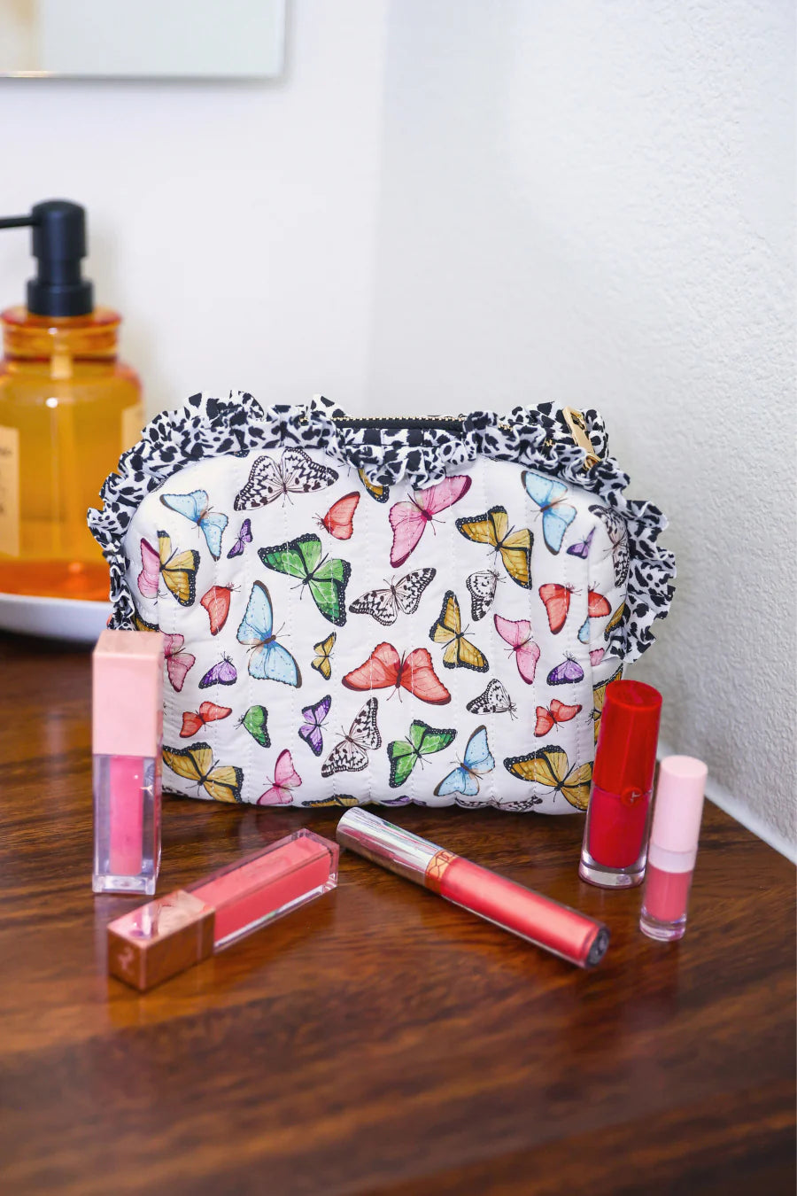 Quilted butterfly print bag with leopard ruffle trim and zipper closure.