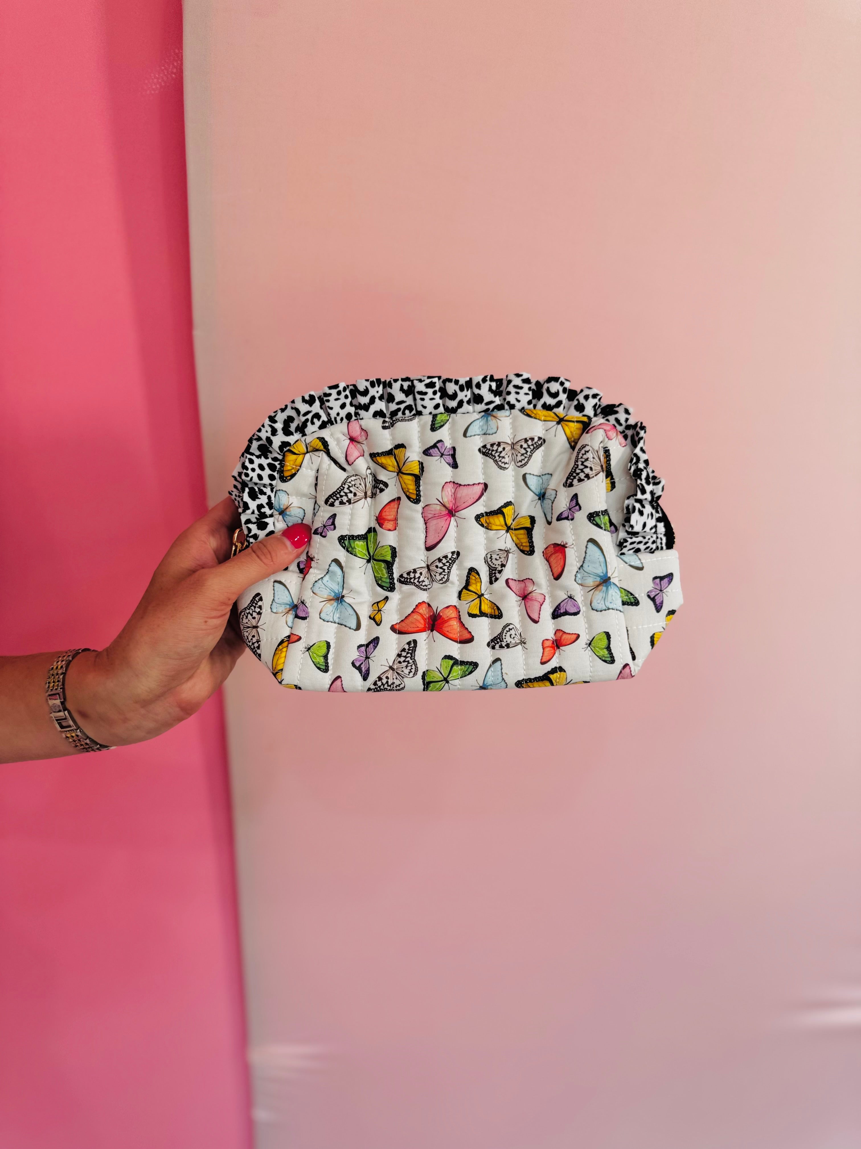 Quilted butterfly print bag with leopard ruffle trim and zipper closure.