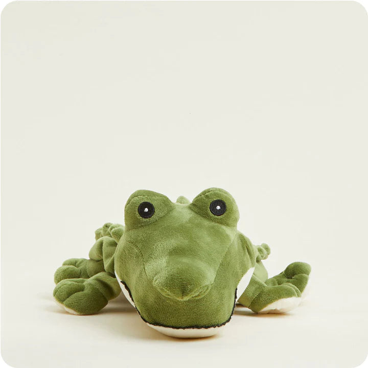 A soft, green plush alligator toy designed to be microwavable, lying down in a relaxed pose.