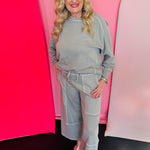 Sleet-colored wide-leg cotton French terry pants with drawstring waistband, contrast seams, cropped raw-edge hem.