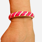 Gold-tone enamel bangle with diagonal red, pink, and white candy cane stripes and a hinge closure.
