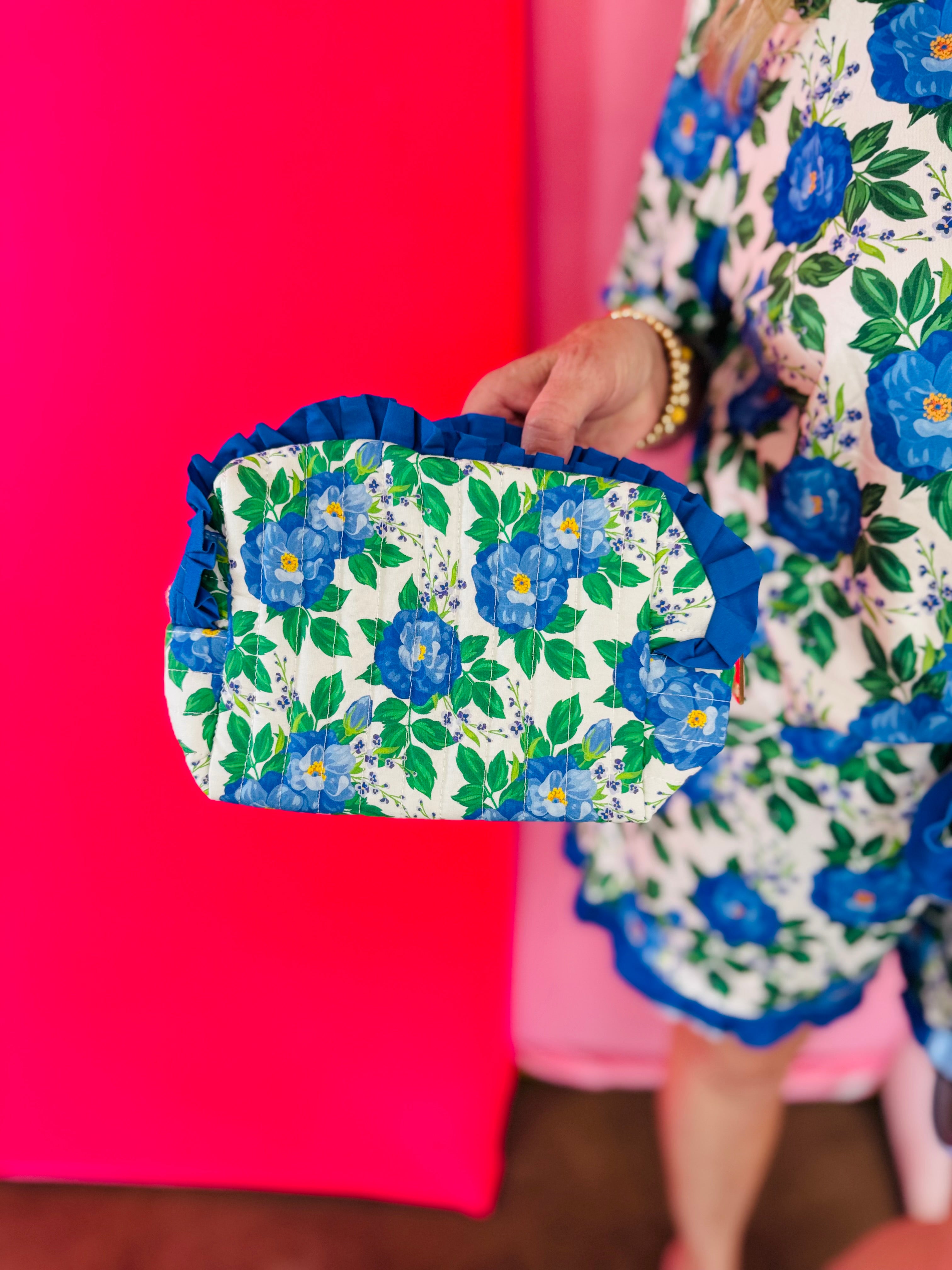 Blue floral quilted bag with ruffle trim and zipper closure.