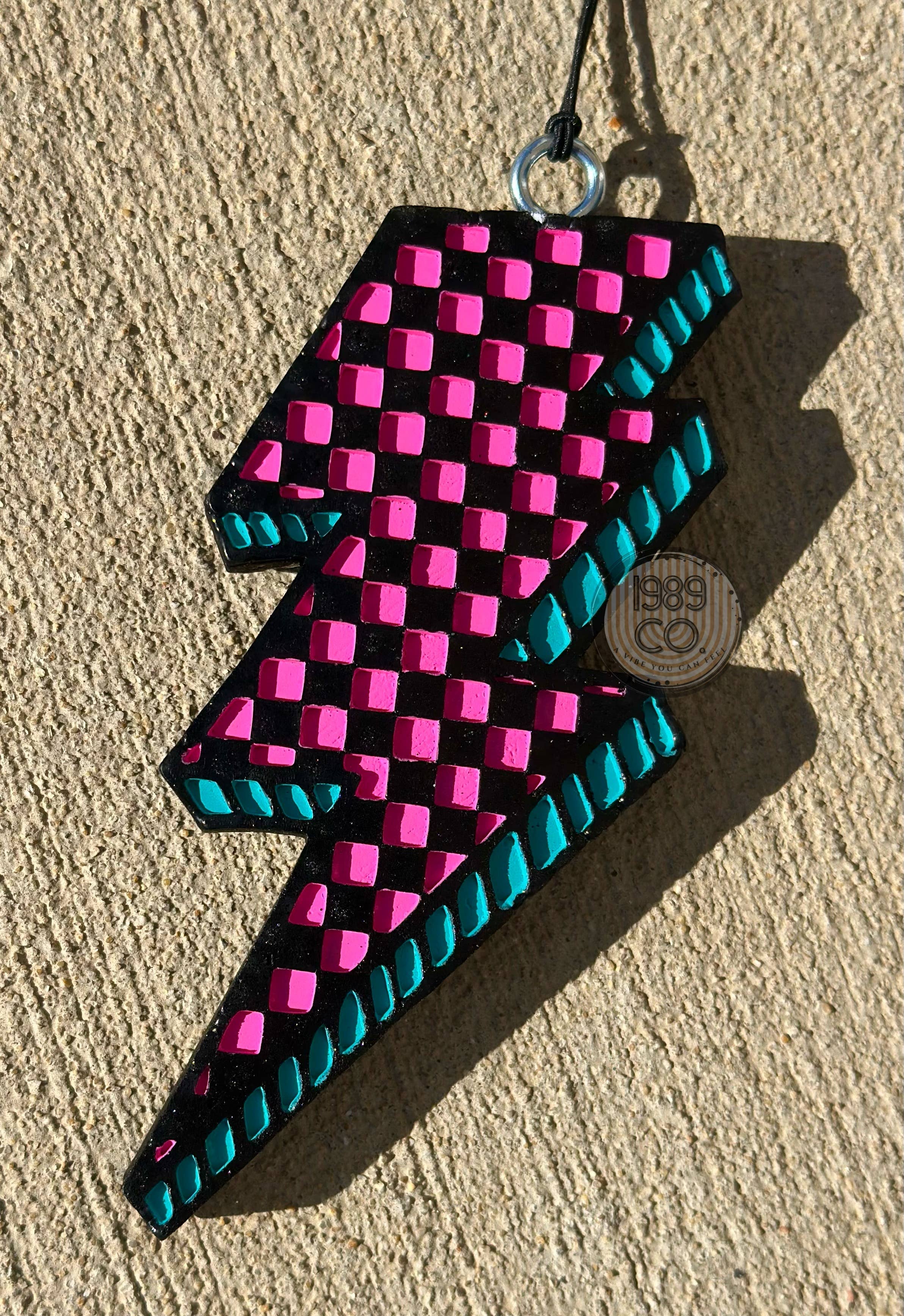 Checkered bolt car freshie with hook and string hanging for long lasting fresh scent.