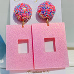 Pink glitter square earrings with sparkling multicolor confetti-style round studs.