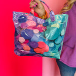 Glossy tote bag with colorful confetti print in turquoise, pink, purple, coral, and blue